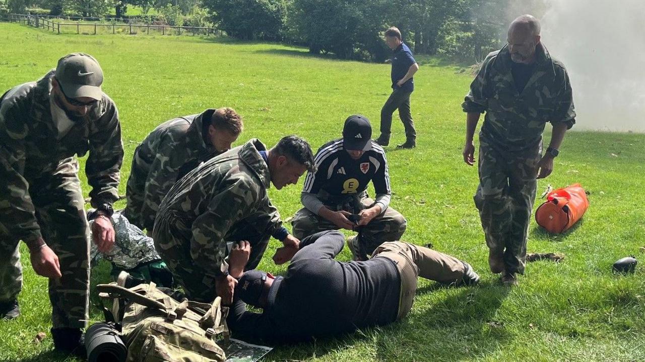 A group including Willy Caballero, Aaron Ramsey and Luke Williams tend to a casualty during a military training exercise as part of the FAW's Uefa pro licence course