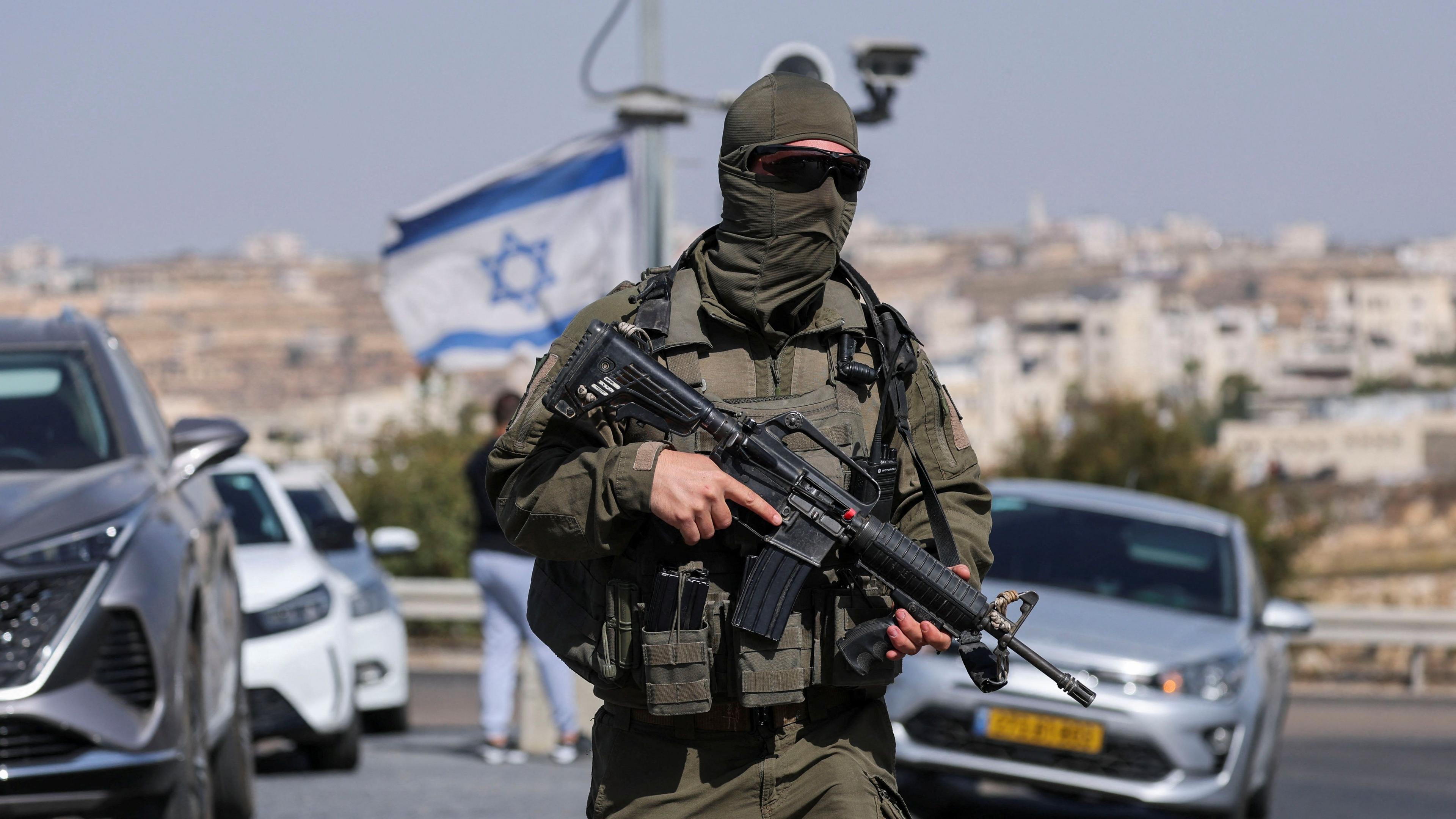 Masked Israeli soldier standing at a military checkpoint